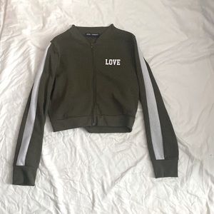 Army green with white stripped sleeves. Cropped zip up jacket. Good condition.